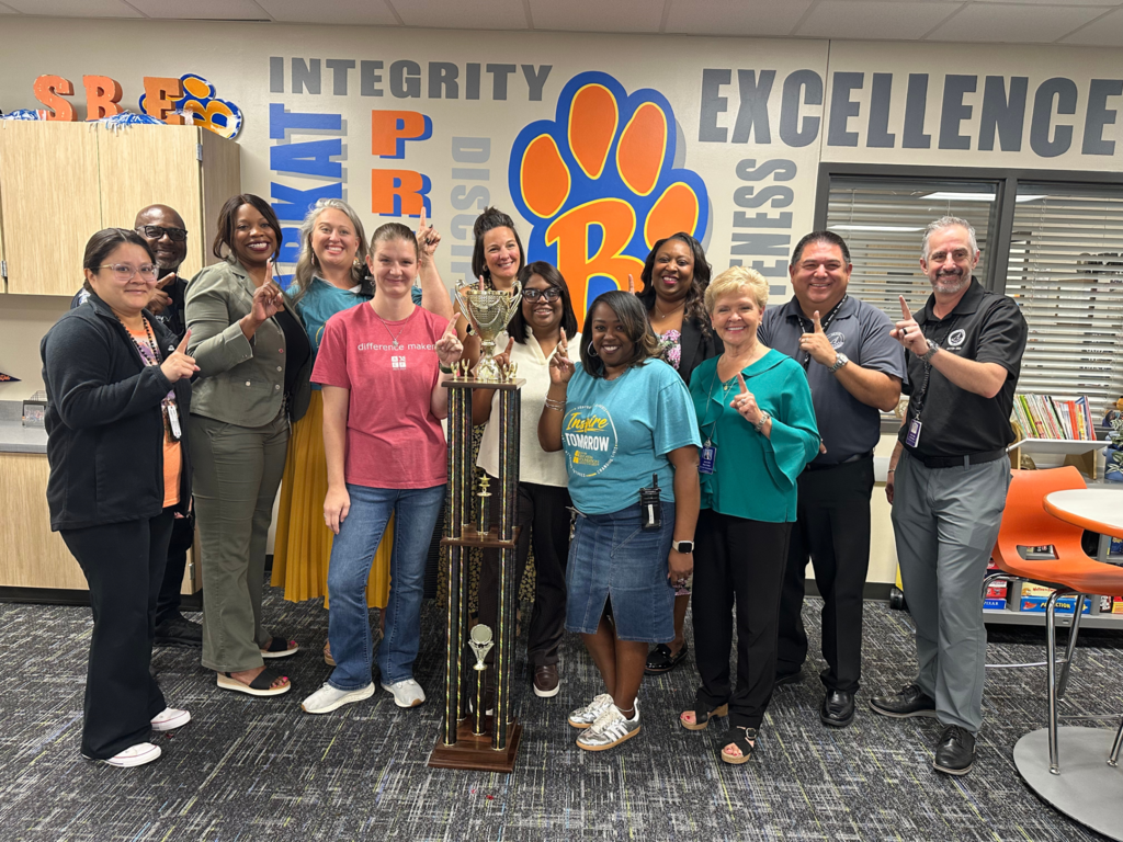 SBE admin and front office staff and district admin posing with the attendance tropy for having the top attendance in the district.