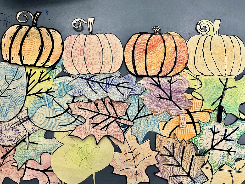 A colorful fall artwork display featuring textured drawings of pumpkins lined up above various autumn leaves.