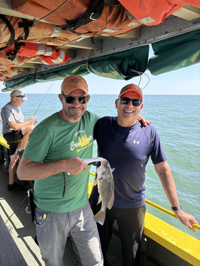 Coach Glatz and Mr. Sliman on a boat holding a fish