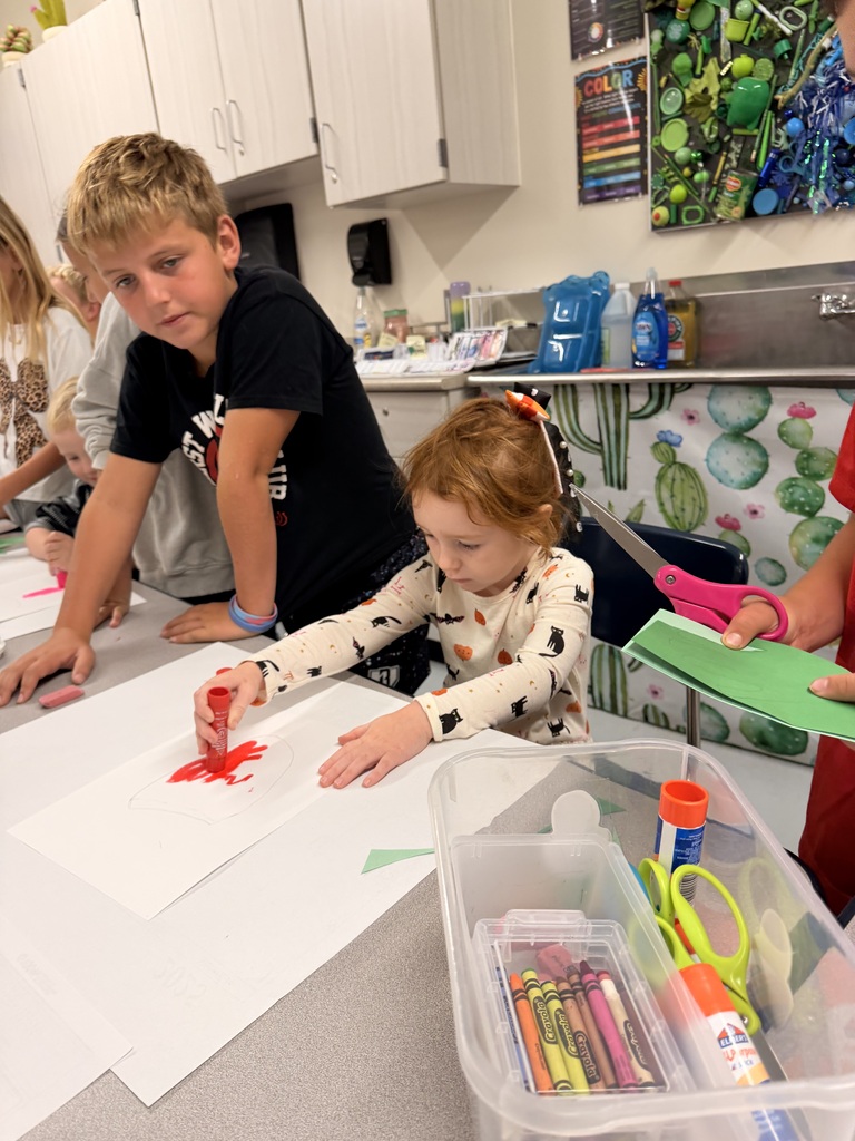Older students help younger students create food themed artwork