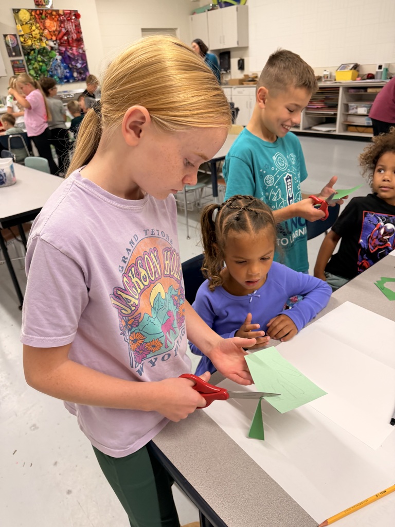 Older students help younger students create food themed artwork