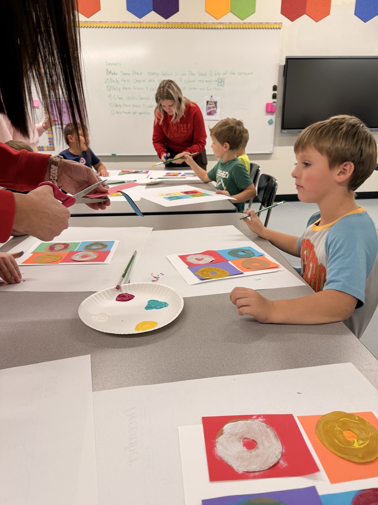 Older students help younger students create food themed artwork