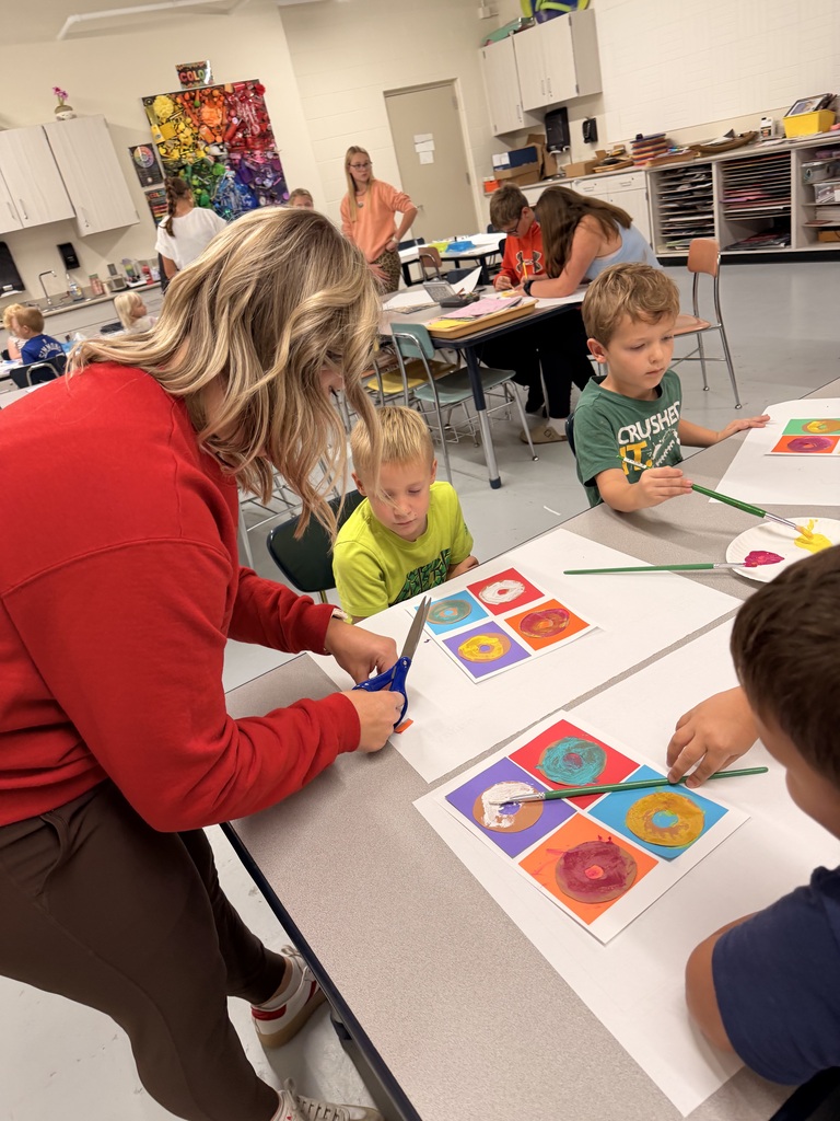 Older students help younger students create food themed artwork