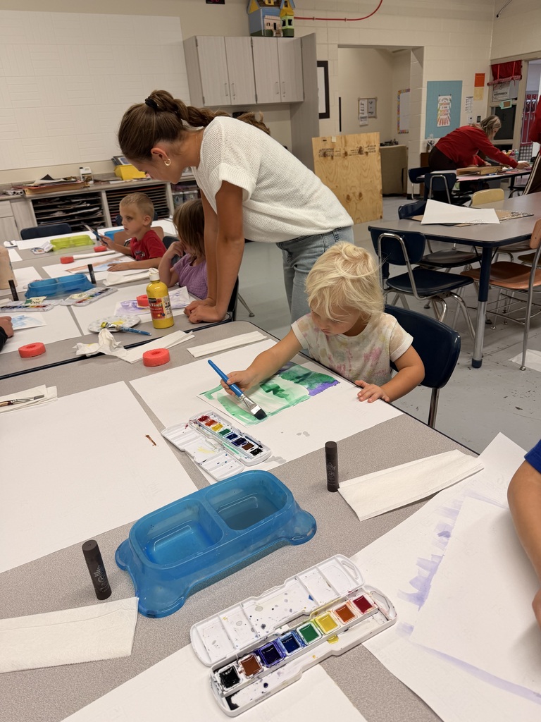 Older students help younger students create food themed artwork