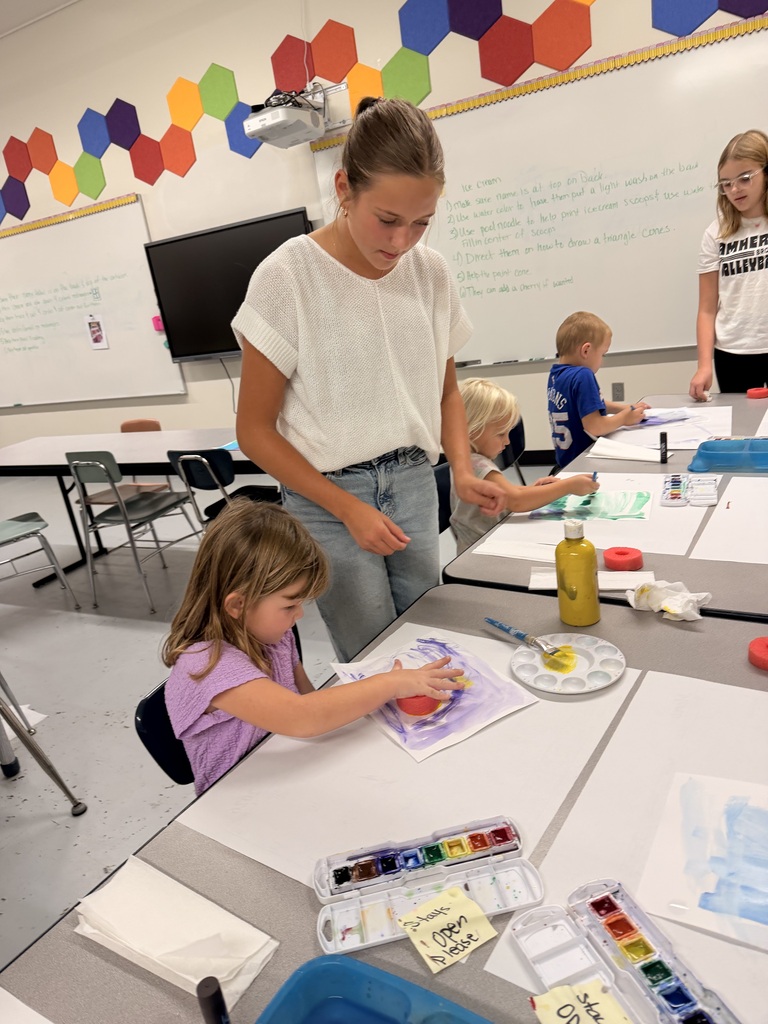 Older students help younger students create food themed artwork