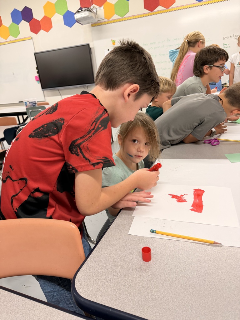 Older students help younger students create food themed artwork