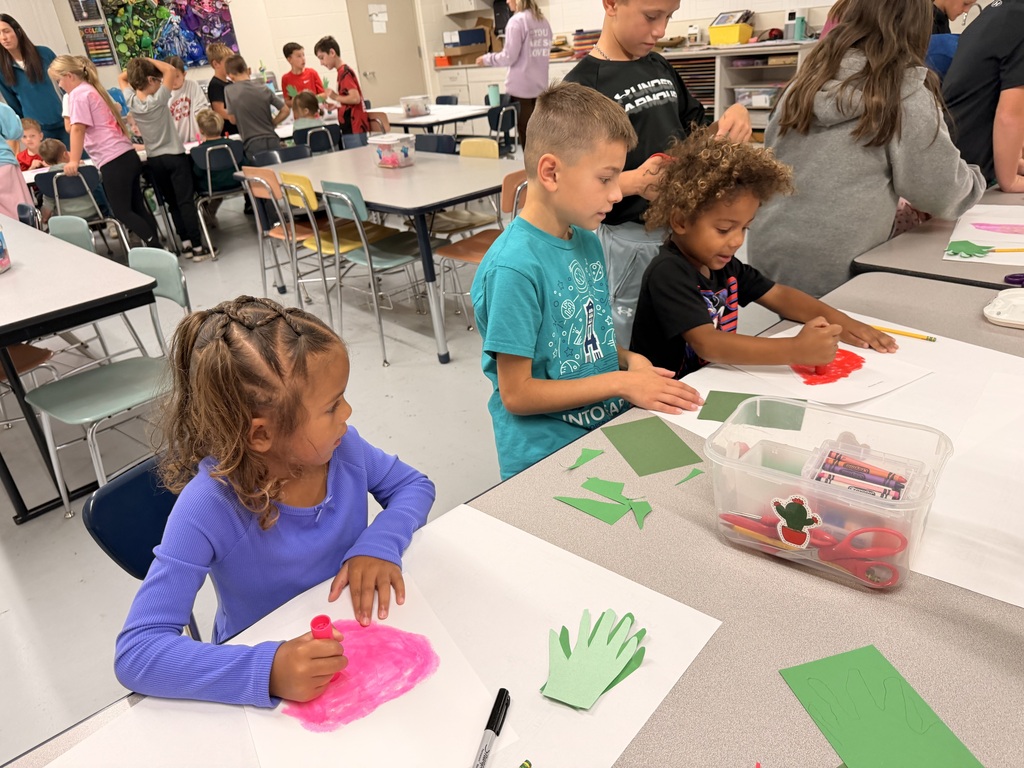 Older students help younger students create food themed artwork