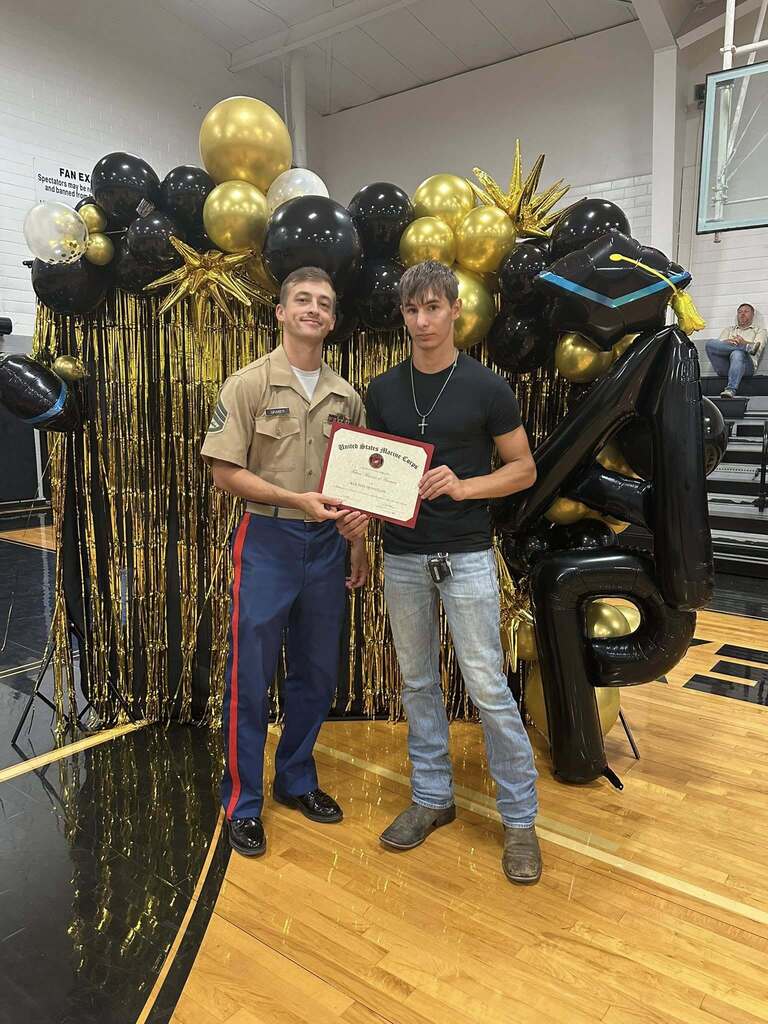 Kolton Hennigan with marines recruiter at 2026 commitment assembly.