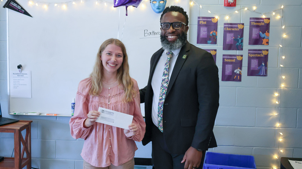 A staff member smiles for a picture with a PTSA representative after receiving a grant