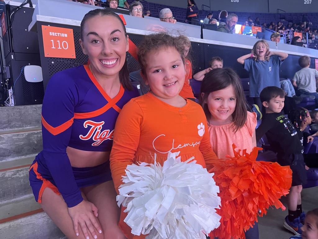 Clemson cheerleader with 2 first grade girls holding pom poms