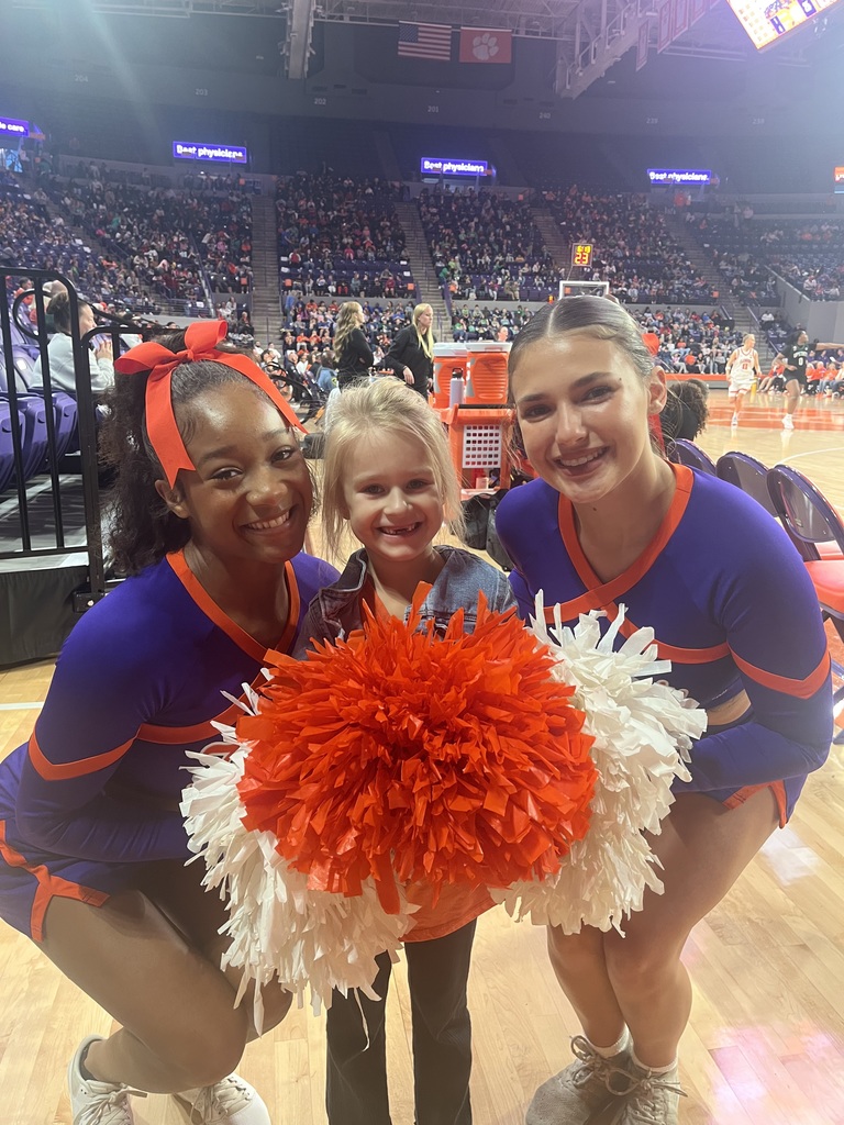 First grade student holding Clemson cheerleaders pom poms
