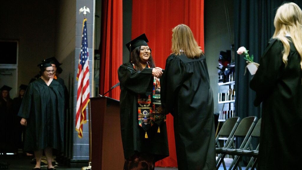 student shaking hands while receiving diploma