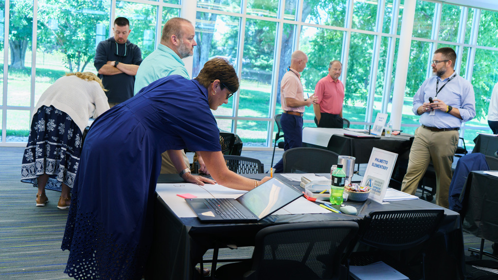 Staff members collaborate and map out their vision for the upcoming school year as they write on a piece of paper