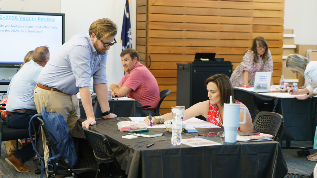 Staff members collaborate and map out their vision for the upcoming school year as they write on a piece of paper