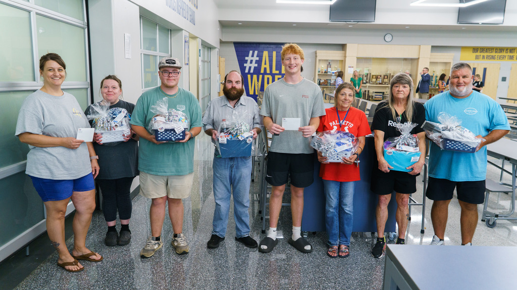 Staff members pose for a photo with the prizes they won during a raffle including gift baskets and gift cards