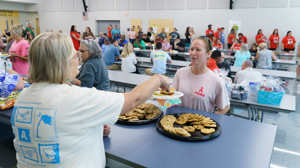 A staff member serves another staff member a cookie on her plate