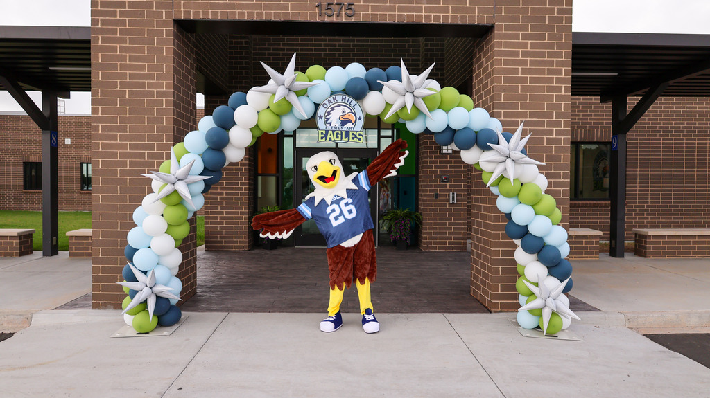 The eagle mascot stands in front of the balloon arch to pose for a photo