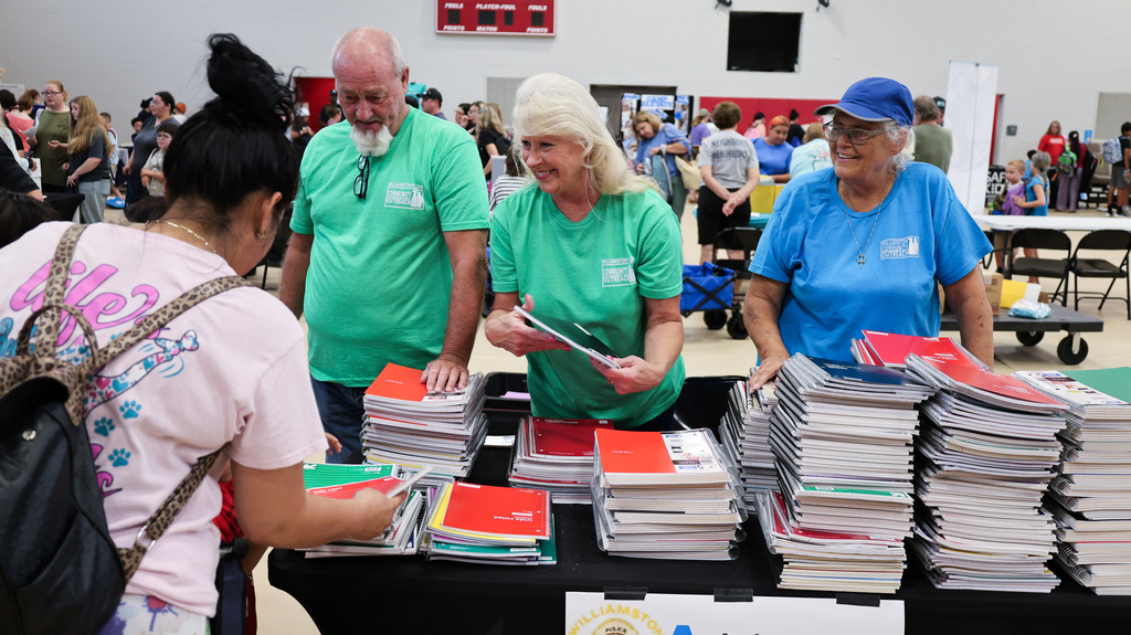Community members hand out a notebook to a family
