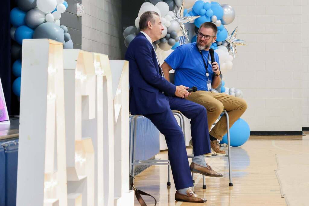 Superintendent Dr. Young and education speaker Todd Whitaker participate in an on-stage conversation during the district's ConnectED professional development event. Decorative blue and white balloons frame the stage as they address educators.