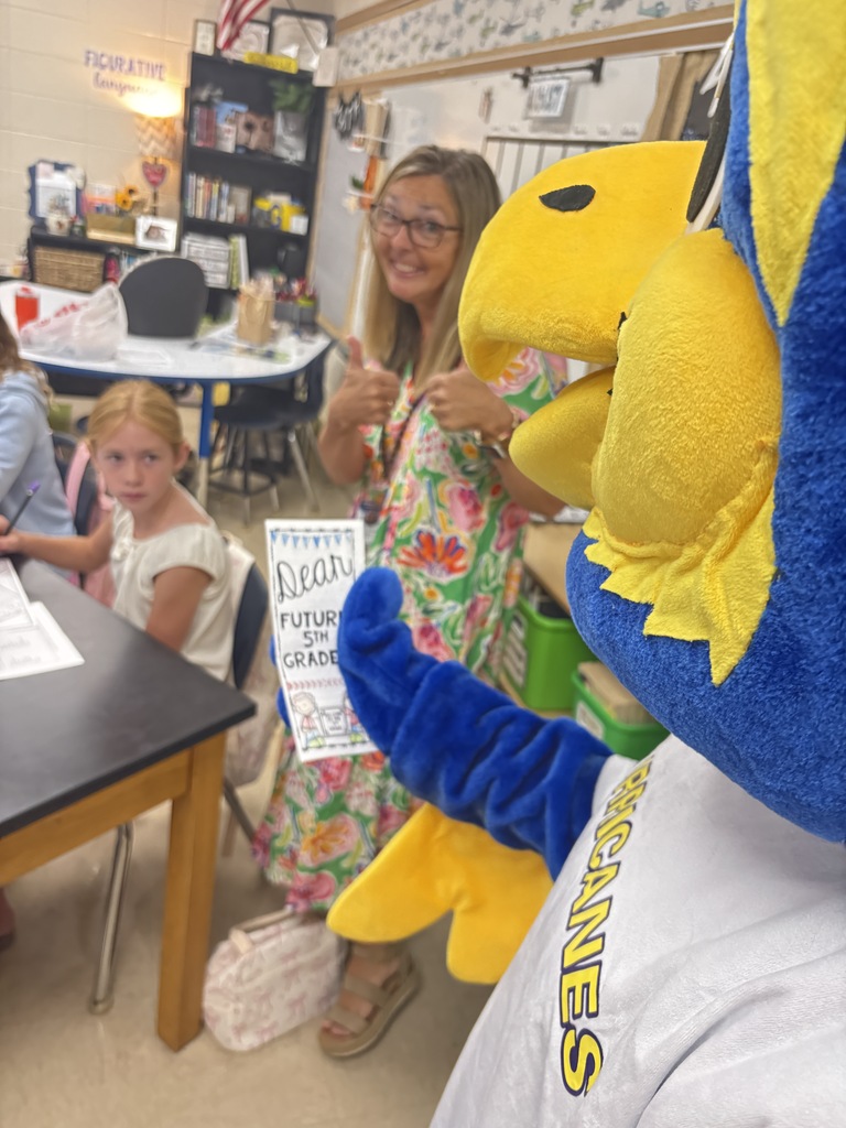 Mascot with Mrs. Gilstrap looking at student work. 