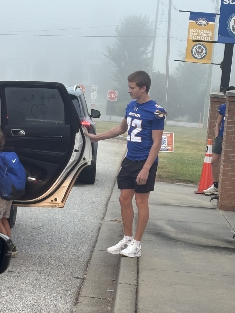Football player opening car door for student