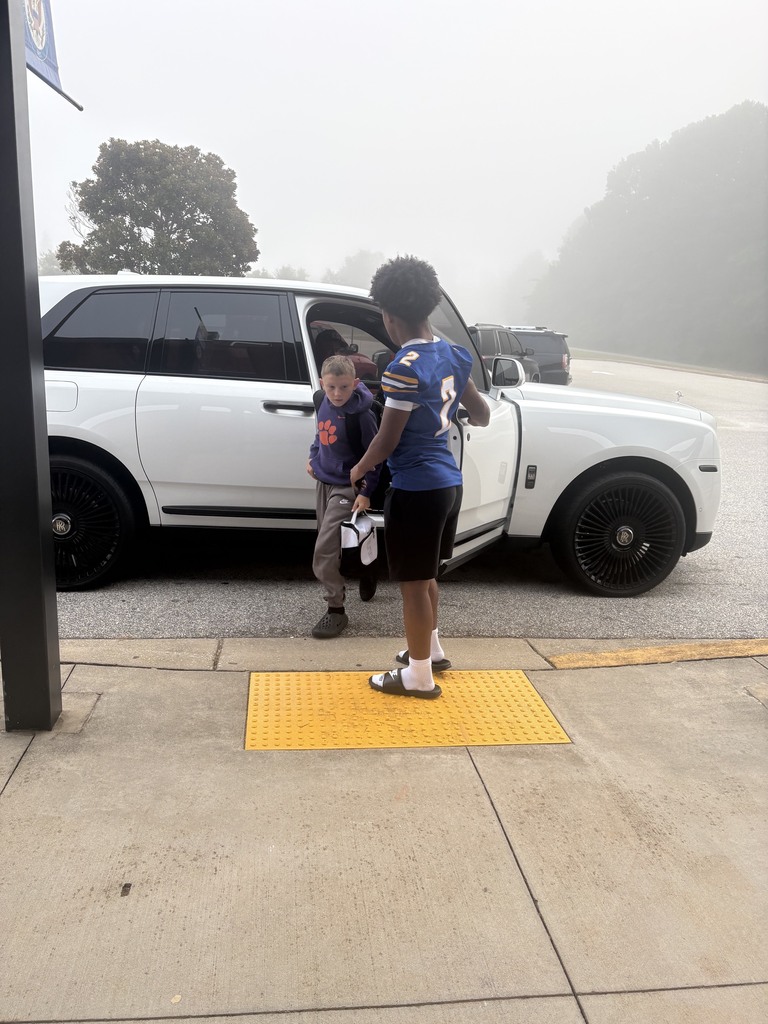 Football player opening door for students