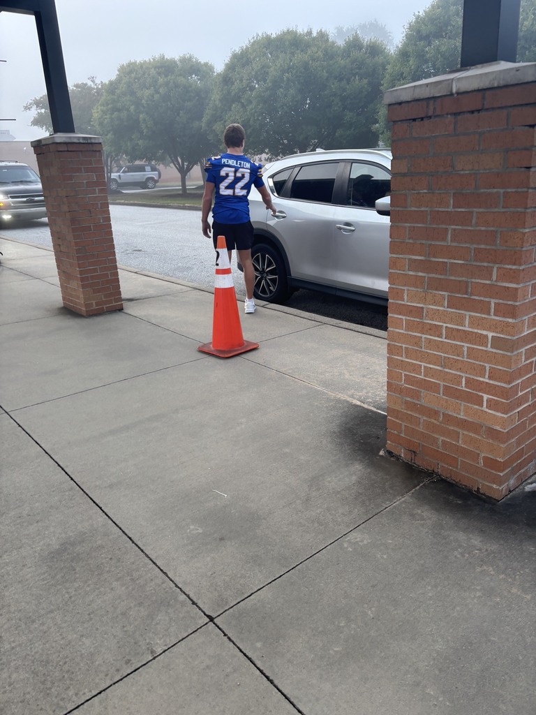 Football player opening car door for students
