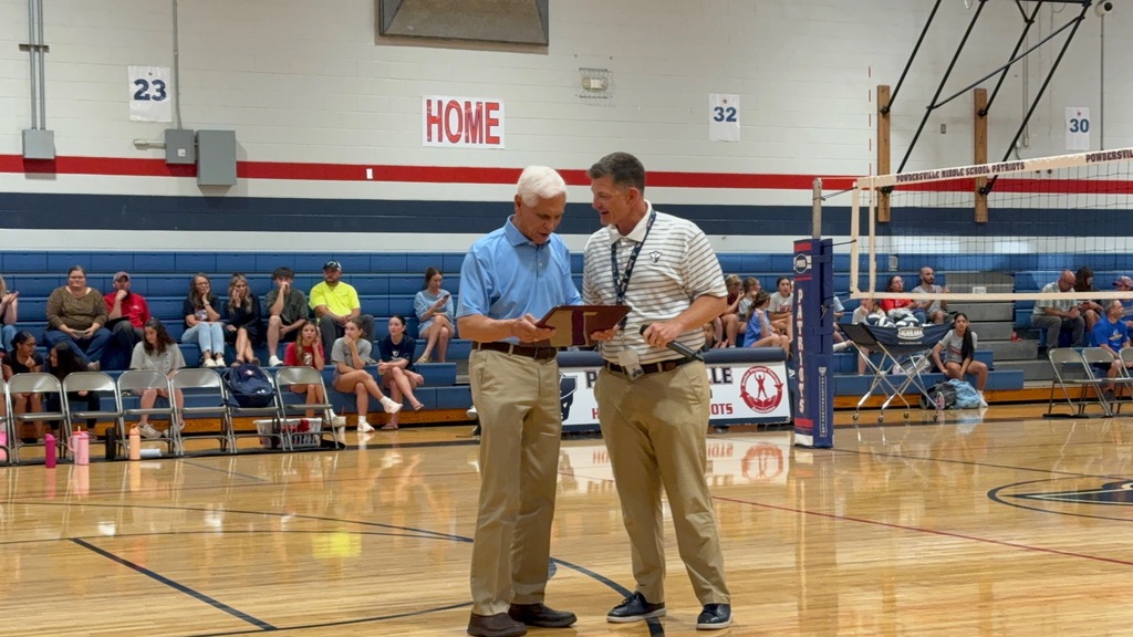 The current school principal presenting the former principal with a plaque honoring him 