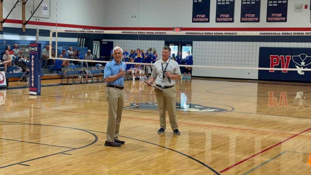 The current school principal presenting the former principal with a plaque honoring him 