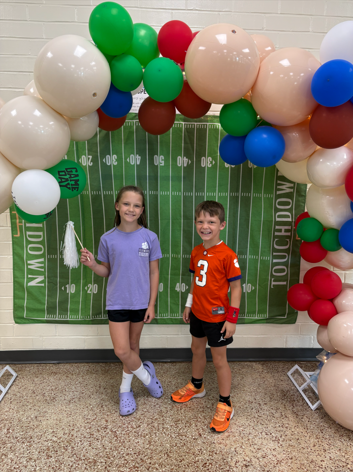 Student pose for a picture in front of the football themed decorations during curriculum night