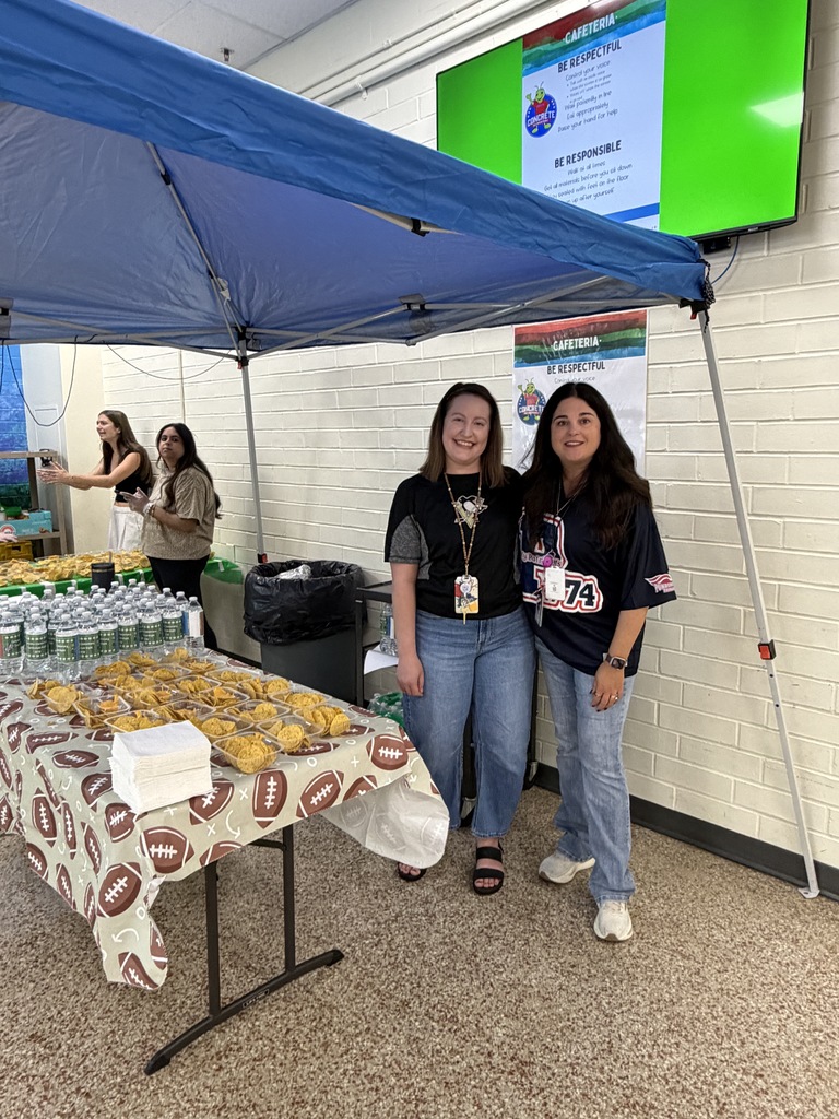 Staff members pose for a picture with tables of food during curriculum night