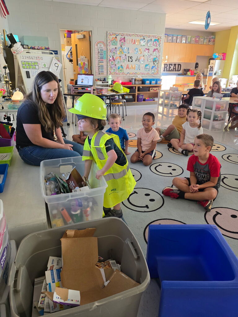 Students participate in a classroom recycling activity while learning about community jobs and responsibilities.