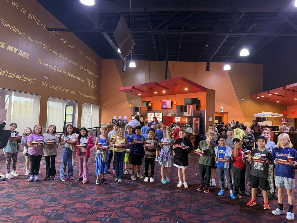 group of students pose for picture inside movie theatre with their popcorn and drinks