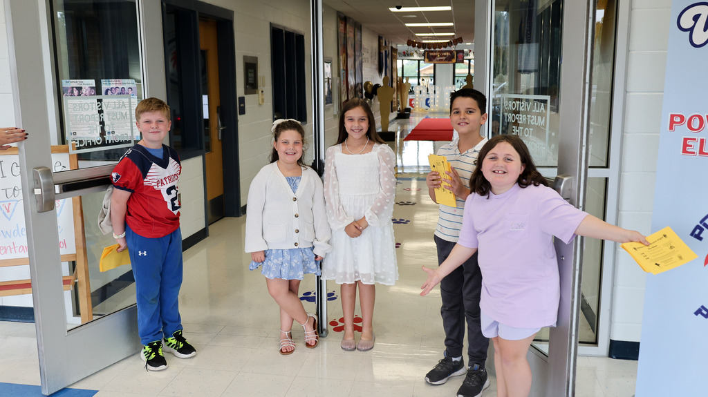 Students smile at the inside entrance of the school