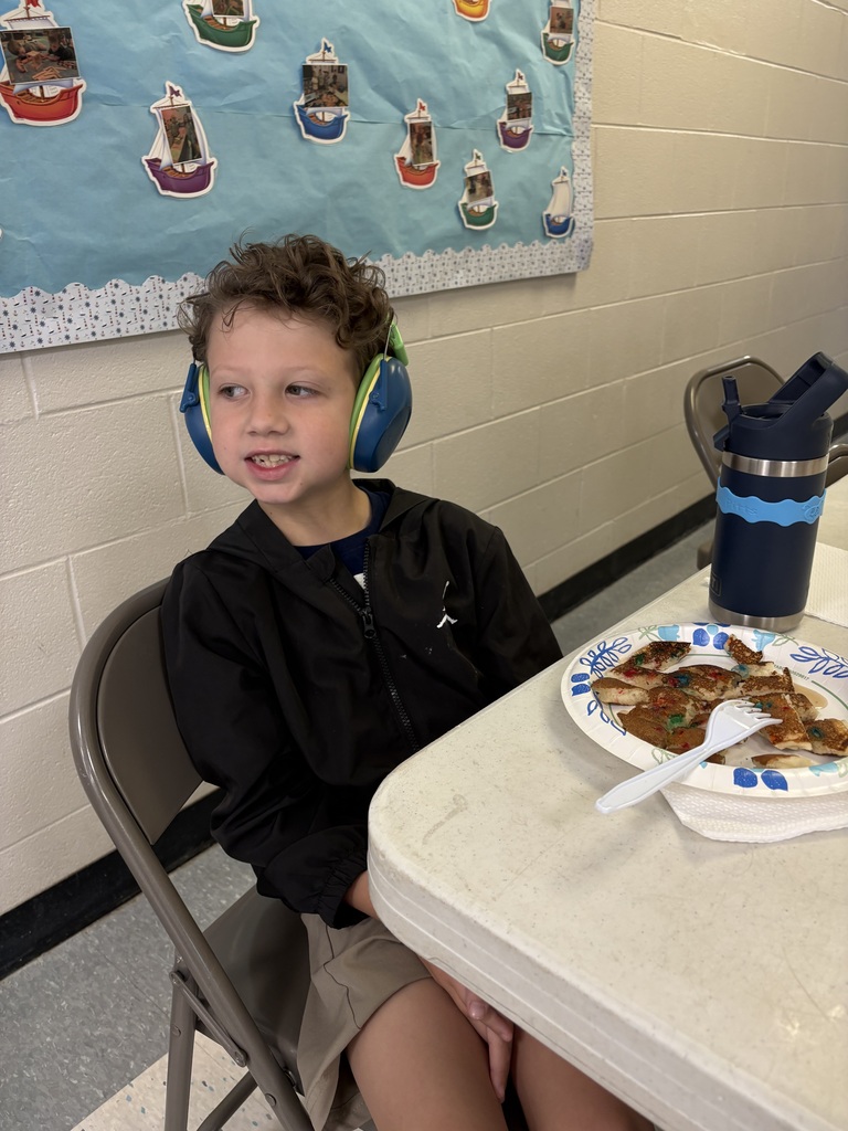 A student smiles for a picture while sitting at a table for the pancake breakfast