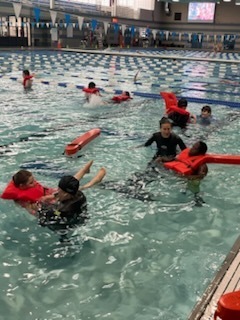 Students in the pool floating with life jackets.