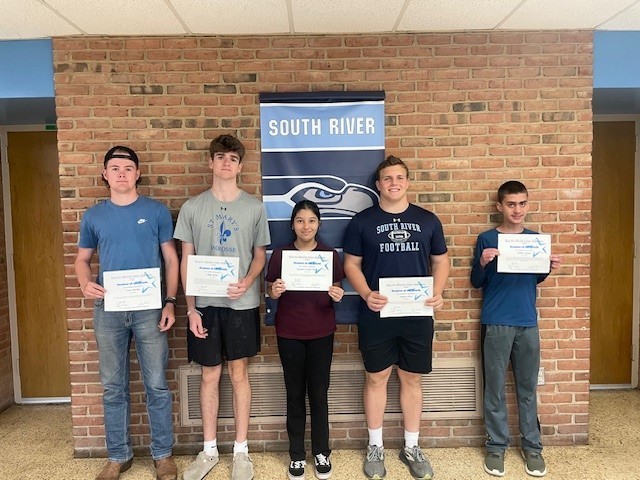 5 students standing together holding certificates