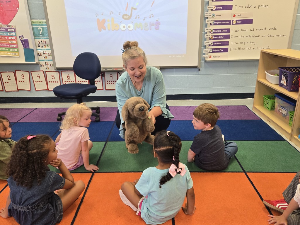 Teacher with puppet kneeling in front of students