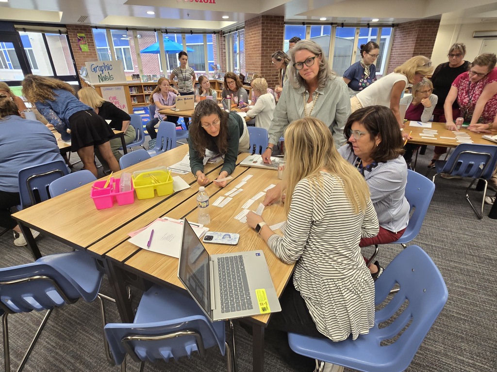 Four teachers working at a table with one teacher standing
