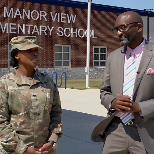Colonel Gore and Dr. Bedell standing in front of Manor View Elementary School