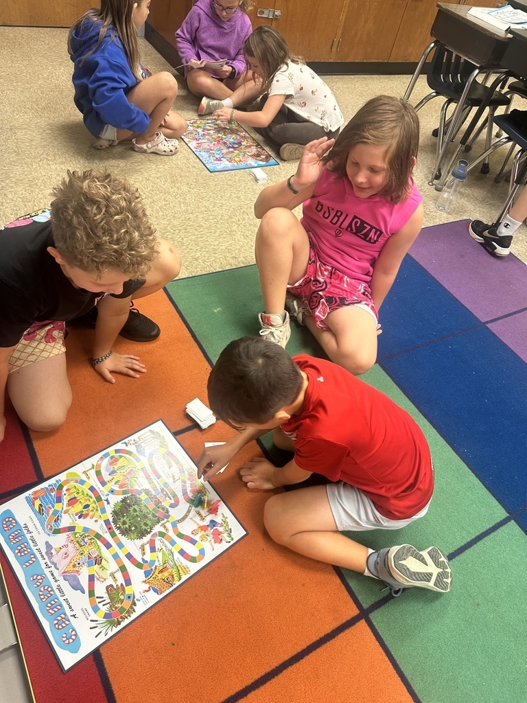 Three students on a colorful rug playing a board game. 