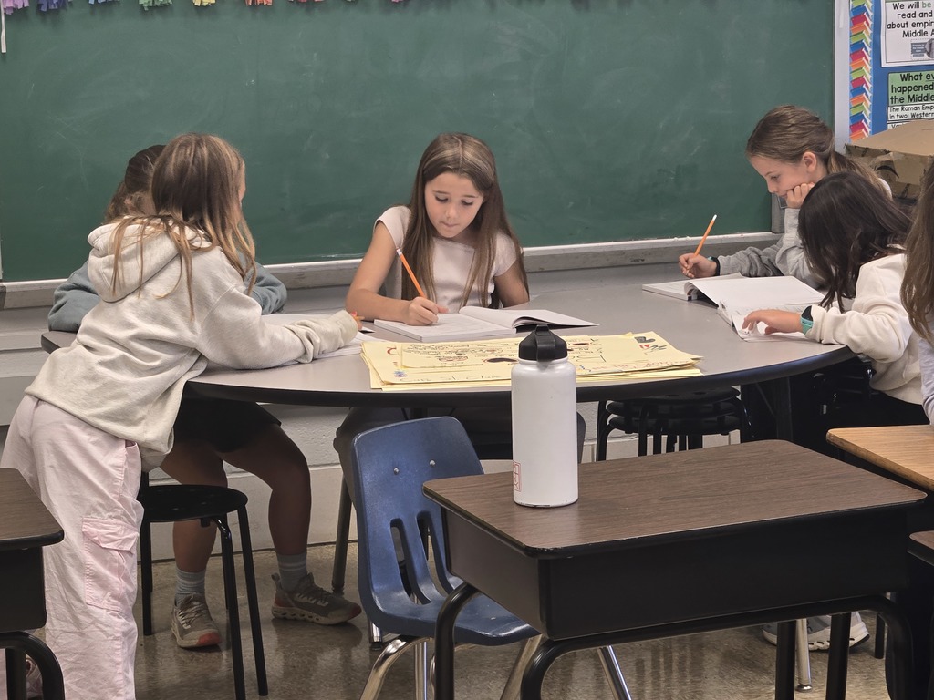 Students writing at u shaped table.