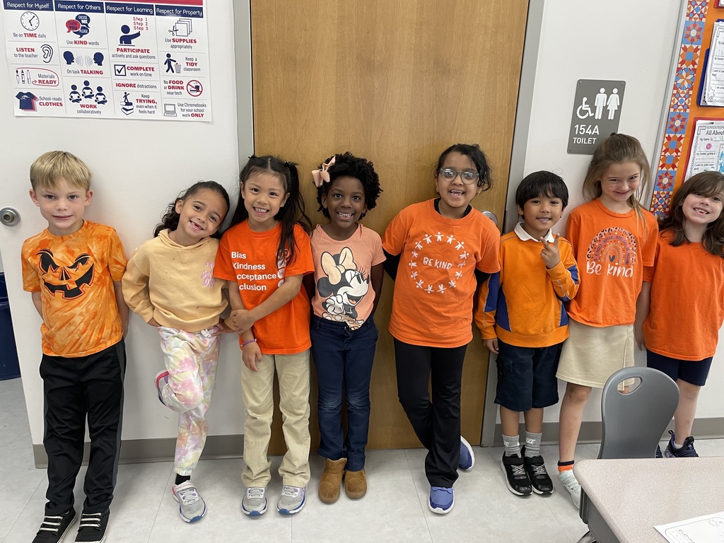 Students dressed in orange, standing together and smiling