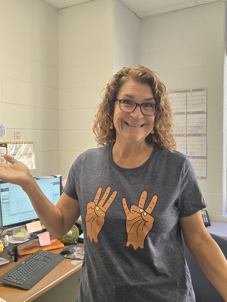 Teacher wearing t-shirt with the sign for 6 and7