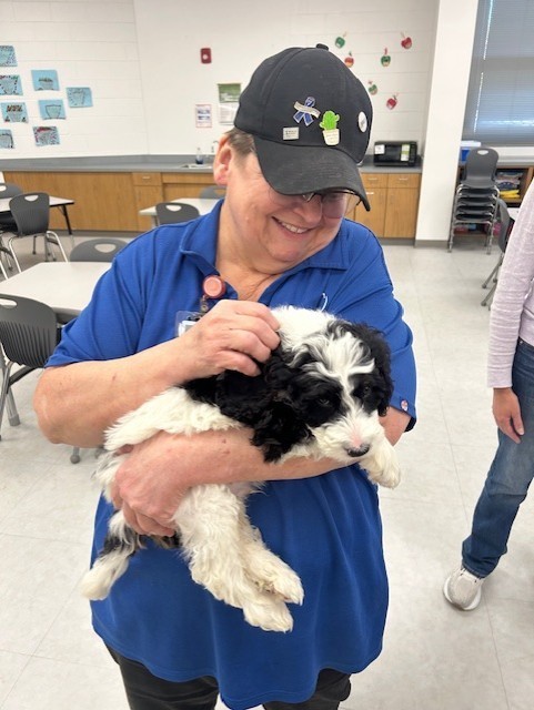 Ms. Dawn holding a black and white puppy, petting its head