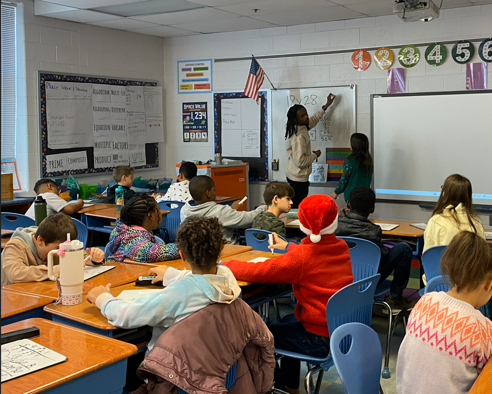 Male teacher at the whiteboard writing down a math equation