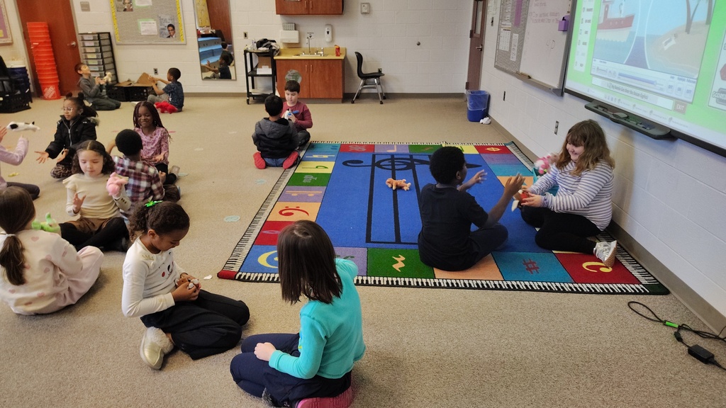 students partnered up facing each other, passing beanie babies