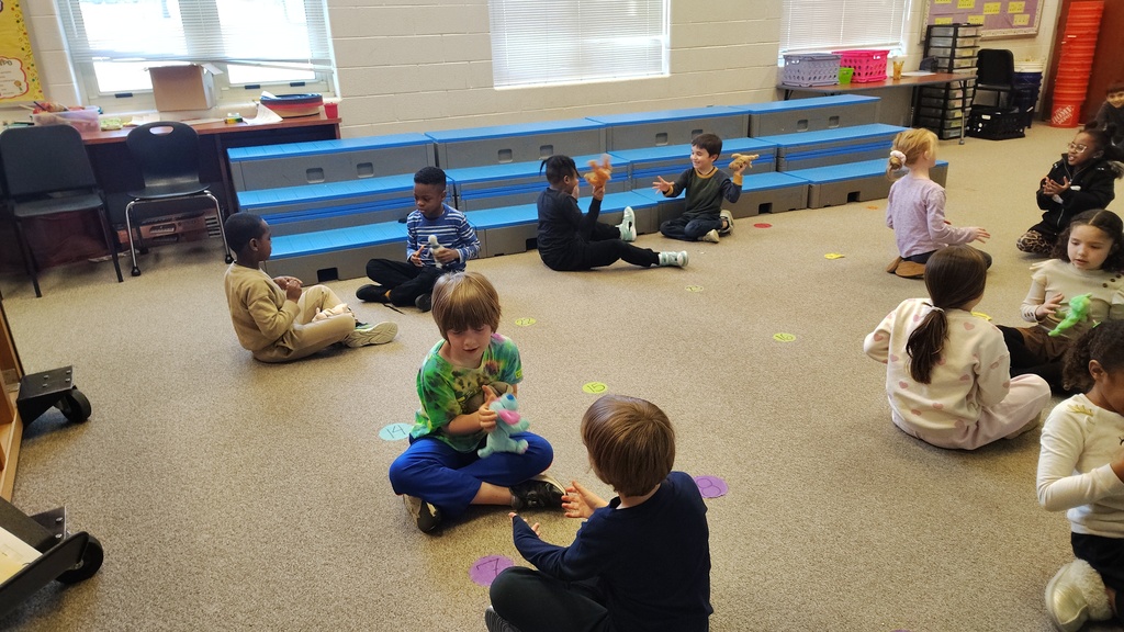 students partnered up facing each other, passing beanie babies
