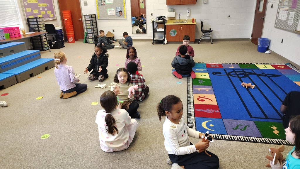 students partnered up facing each other, passing beanie babies