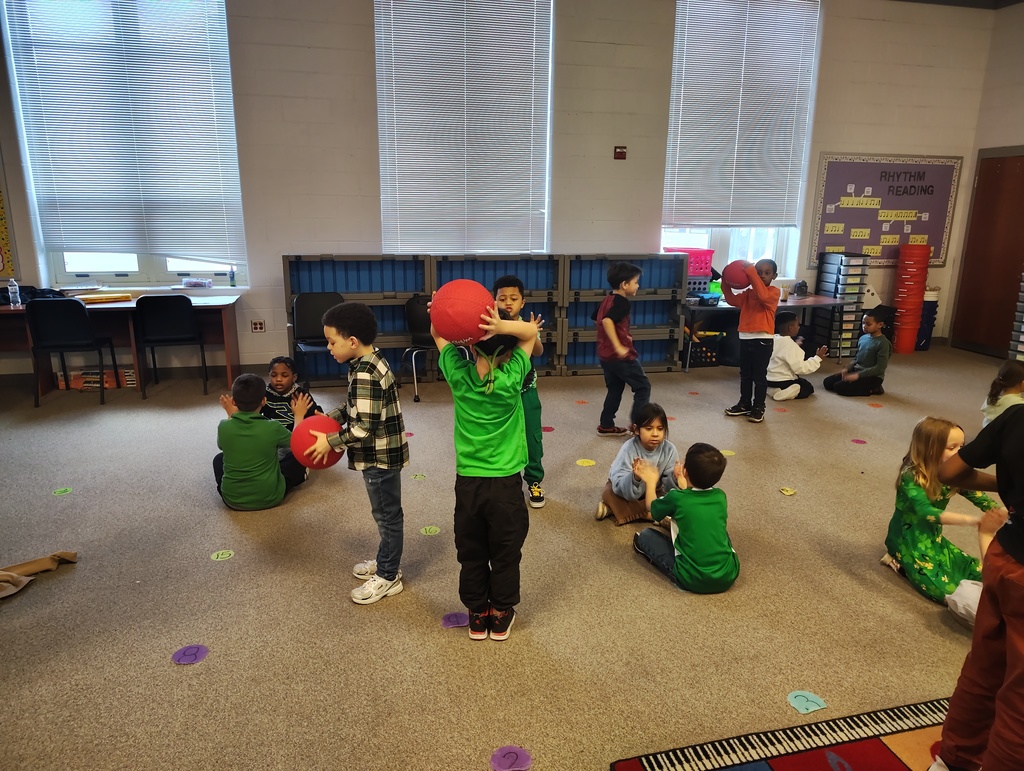 students in a music room using a red kick ball